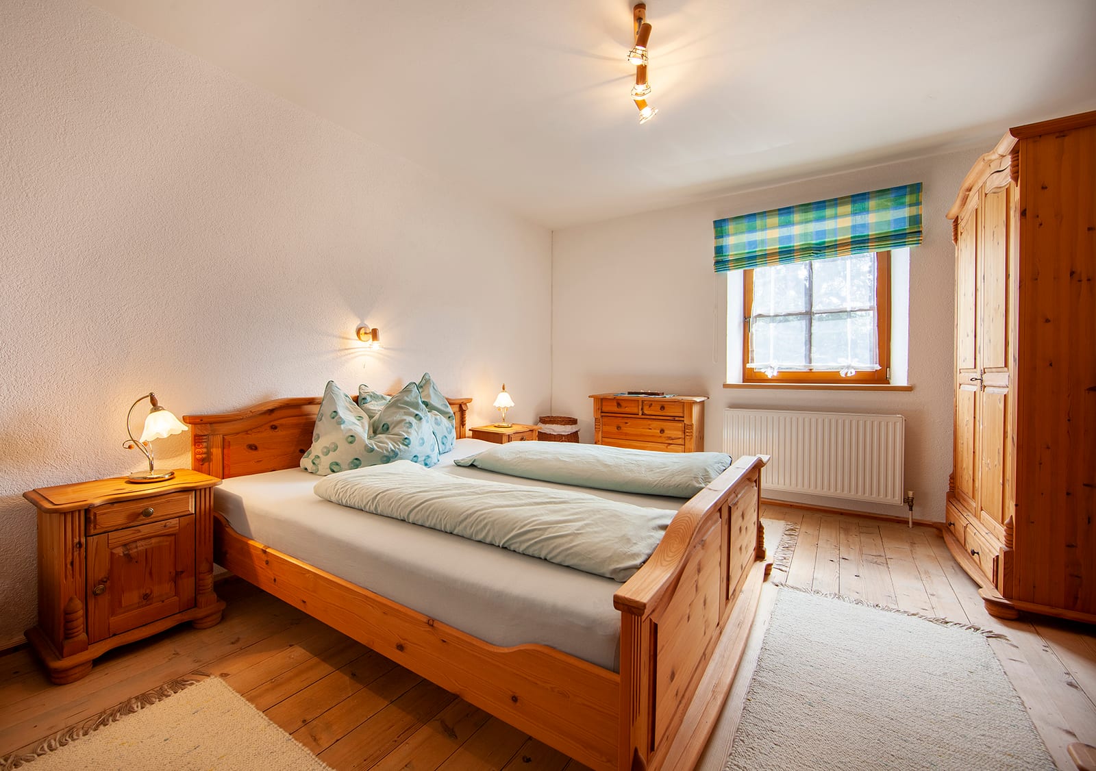 Schlafzimmer mit Doppelbett aus Holz und Bauernkasten